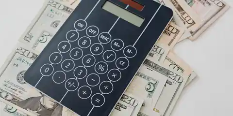 Calculator resting on banknotes while working out ticketing costs