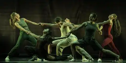 Dance company performing synchronized choreography on stage