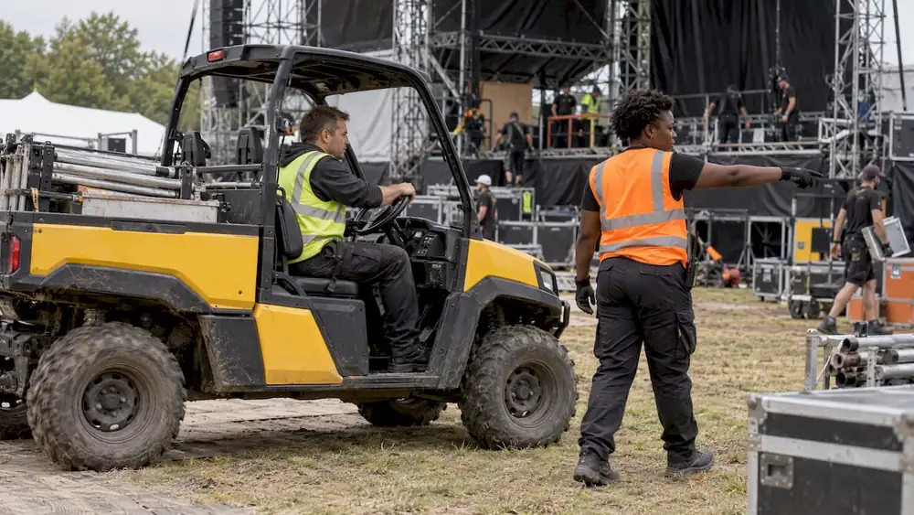 Equipo de trabajo guiando un vehículo durante el montaje de un festival