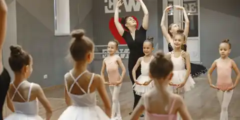 Ballet teacher guiding young students in a studio