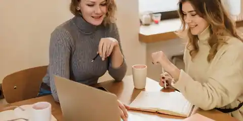 Two people sitting at a table working through something together on a laptop
